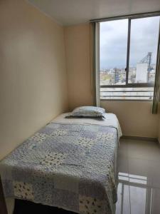 a small bedroom with a bed and a window at Departamento amplio y acogedor San Miguel in Lima