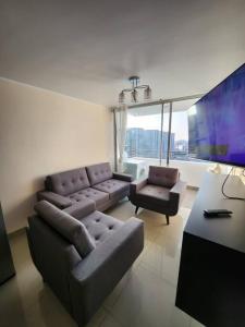 a living room with two couches and a tv at Departamento amplio y acogedor San Miguel in Lima