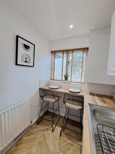 a kitchen with a table and two stools in it at Beachwood House, Serviced Accommodation in Brumby