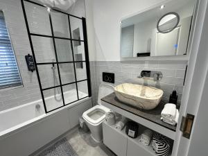 a bathroom with a sink and a tub and a toilet at A luxury brand-new apartment in Barnet