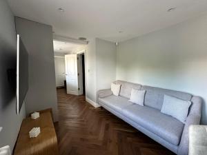 a living room with a gray couch and a wooden floor at A luxury brand-new apartment in Barnet