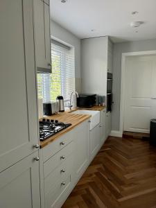 una cucina con armadi bianchi e piano cottura di A luxury brand-new apartment a Barnet