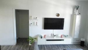 ein weißes Wohnzimmer mit einem TV an der Wand in der Unterkunft Last Moon in Flic-en-Flac