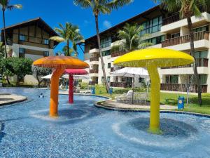 ein Pool mit drei Sonnenschirmen im Wasser in der Unterkunft Marulhos Suítes Resort Muro Alto Beira Mar por Brevelar in Porto De Galinhas