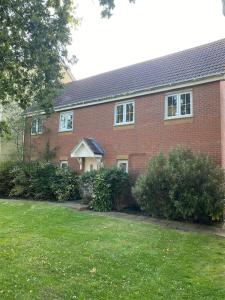 a red brick house with a lawn in front of it at Contemporary Coach House in Newport, Isle of Wight in Newport