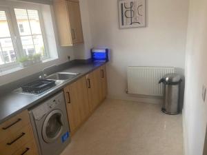 a kitchen with a sink and a washing machine at Contemporary Coach House in Newport, Isle of Wight in Newport