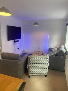 a living room with two couches and a flat screen tv at Contemporary Coach House in Newport, Isle of Wight in Newport