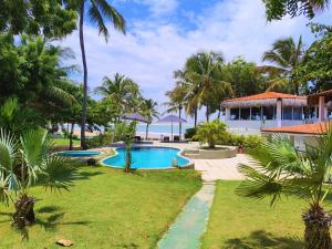 a resort yard with a swimming pool and palm trees at Pousada Les Alizes in Icaraí