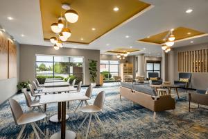 メカニクスバーグにあるTownePlace Suites by Marriott Harrisburg West/Mechanicsburgのテーブルと椅子と窓のあるロビー