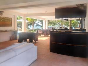 a living room with a white couch and a piano at OP Apartahotel Pedasí Ocean Properties in Pedasí Town