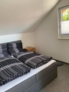 ein Schlafzimmer mit einem Bett mit gestreiften Kissen und einem Fenster in der Unterkunft Ferienwohnung Valentin in Passau