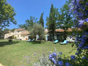 ein Haus mit einem Hof mit blauen Bänken und Blumen in der Unterkunft Mas Antonine Cigalle in Arles