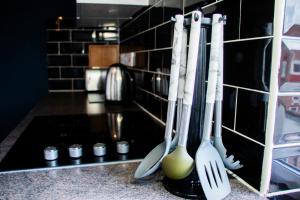 a kitchen counter with utensils hanging on a wall at Cozy Flat Reading City Centre Available for Contractors in Reading
