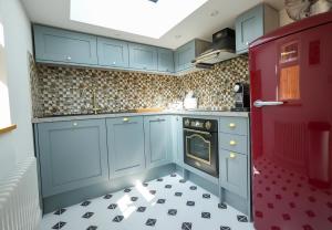 eine Küche mit blauen Schränken und einem schwarz-weißen Boden in der Unterkunft Fleur de Sel - Upside Down Cottage with Spectacular View & Parking in Brixham + 18 Fotos