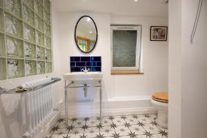 ein Badezimmer mit Waschbecken, Spiegel und Toilette in der Unterkunft Fleur de Sel - Upside Down Cottage with Spectacular View & Parking in Brixham