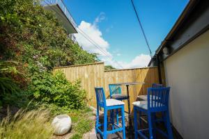 drei blaue Stühle und ein Tisch auf einer Terrasse in der Unterkunft Fleur de Sel - Upside Down Cottage with Spectacular View & Parking in Brixham