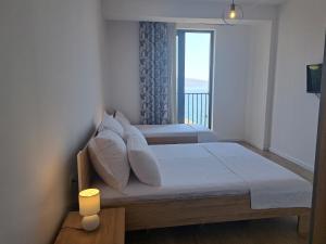 a bedroom with two beds and a window at Mamani Apartments Saranda in Sarandë