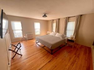 a bedroom with a bed and wooden floors and windows at The Big Farm House in Erie