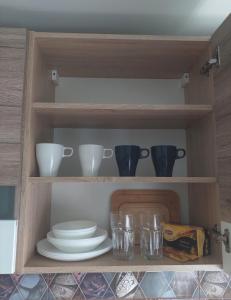 a cupboard with plates and bowls and glasses at Vegus apartment in Naujoji Akmenė