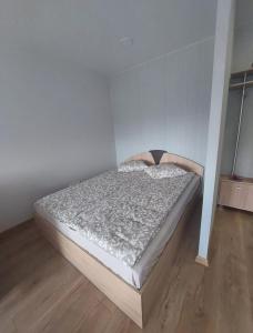 a bed in a room with a white wall at Vegus apartment in Naujoji Akmenė