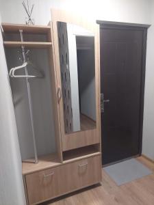 a wooden cabinet with a mirror and a door at Vegus apartment in Naujoji Akmenė