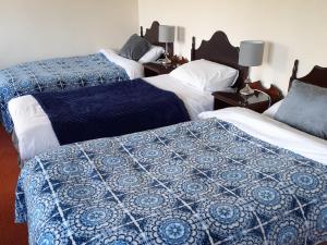 a bedroom with two beds with blue and white blankets at An Chéibh B&B in Rossaveel