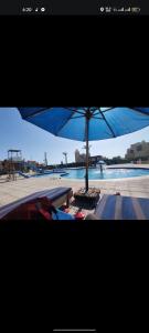 Adam Villa New Venecia El Ain El Sokhna في العين السخنة: وجود مظلة زرقاء للجلوس بجانب المسبح