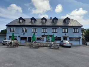 An Chéibh B&B في Rossaveel: مبنى أزرق كبير مع طاولات نزهة أمامه