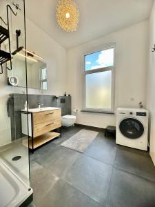 a bathroom with a sink and a washing machine at Exklusives City-Apartment im Herzen Oldenburgs mit Balkon und Parkplatz A36 in Oldenburg