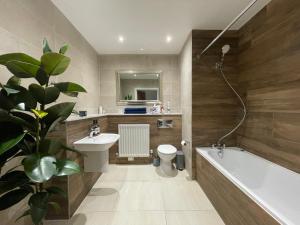 ein Badezimmer mit einem Waschbecken, einer Badewanne und einem WC in der Unterkunft Quiet Luxe Home with GYM and Free Parking in Thamesmead