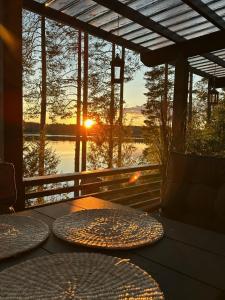 eine Terrasse mit einem Tisch und Blick auf den Sonnenuntergang im Hintergrund in der Unterkunft Cityvilla on the shore of Lake Haapajärvi in Joensuu