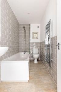 ein Badezimmer mit einer weißen Badewanne und einem WC in der Unterkunft Gorgeous London Town House Sleeps up to 8 in London