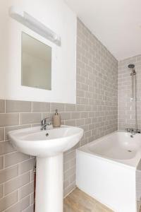 a white bathroom with a sink and a bath tub at Gorgeous London Town House Sleeps up to 8 in London
