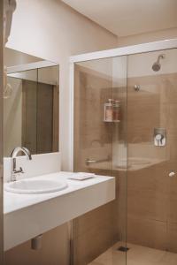 a bathroom with a sink and a glass shower at Hotel Serrano in Campina Grande