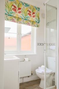 a bathroom with a toilet and a window at The Cobblers, Luxury Coastal House for 16 in Wells next the Sea