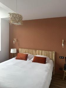 una camera da letto con un grande letto bianco con due cuscini di Hôtel Le Dormeur du Val a Charleville-Mézières