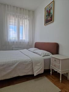 a bedroom with a bed and a dresser and a window at Dimitra apartman in Šabac