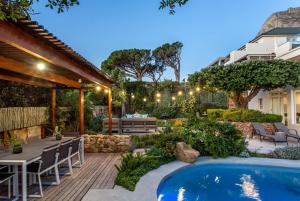 a backyard with a pool and a table and chairs at Far Horizons Camps Bay in Cape Town