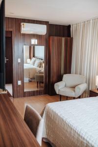 a bedroom with a bed and a chair and a mirror at Hotel Serrano in Campina Grande