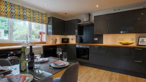 a kitchen with black cabinets and a table with wine glasses at Cobblers Cottage, Wells Next The Sea in Wells next the Sea