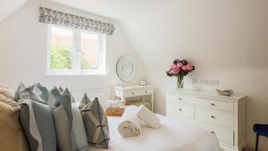 - une chambre blanche avec un lit et un vase de fleurs dans l'établissement Cobblers Cottage, Wells Next The Sea, à Wells-next-the-Sea