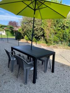 einem schwarzen Tisch mit zwei Stühlen und einem Sonnenschirm in der Unterkunft Maison de campagne in Champvans