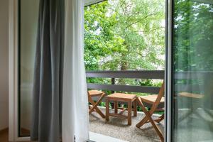 einen Balkon mit einem Tisch und Stühlen mit Blick aus dem Fenster in der Unterkunft Inn Joy Apartments - Sankt Gallen West in St. Gallen