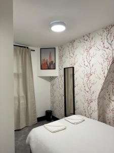 1 dormitorio con cama blanca y papel pintado de color rosa en Ivy House Hotel, en Londres