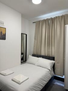 a bedroom with a bed with white sheets and a window at Ivy House Hotel in London