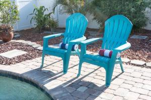 twee blauwe stoelen naast een zwembad bij Coral Cottage pool/firepit a 2 bed 2 bth sleeps 6 in Palm Harbor