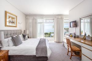 a bedroom with a bed and a desk and a window at Far Horizons Camps Bay in Cape Town