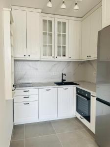 a white kitchen with white cabinets and a sink at Apartment Park in Novi Sad