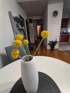 un vaso bianco con fiori gialli seduto su un tavolo di Apartman Jurak a Zaprešić