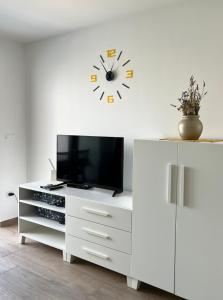 a white cabinet with a tv and a clock on a wall at Katarina in Primošten